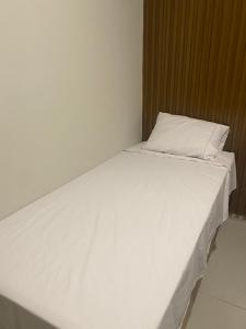 a bed with white sheets and a pillow on it at Origem in Mamanguape