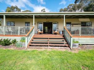 a house with a large wooden deck in front of it at Woodview Cottage Farm stay in Port Welshpool