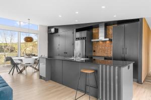 a kitchen with black cabinets and a dining room at The Chocolate Box - Waipu Cove Holiday Home in Waipu