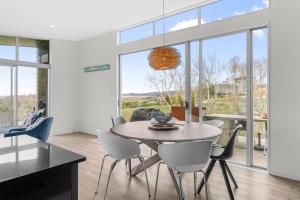 a dining room with a table and chairs at The Chocolate Box - Waipu Cove Holiday Home in Waipu +29 photos