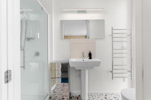 a white bathroom with a sink and a shower at The Chocolate Box - Waipu Cove Holiday Home in Waipu