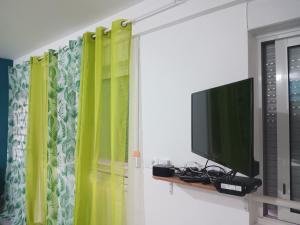 a living room with a tv and green curtains at Ado Mishkan in Cayenne