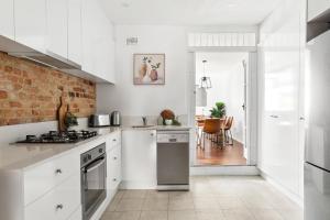 a kitchen with white cabinets and a brick wall at Stylish Darlinghurst Townhouse l 3 Bedrooms in Sydney