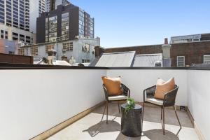 two chairs on a balcony with a view of a city at Stylish Darlinghurst Townhouse l 3 Bedrooms in Sydney