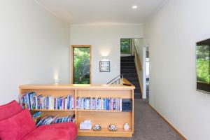a living room with a red couch and books at Tironui Lake Tarawera in Lake Tarawera