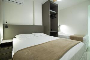 Un dormitorio con una gran cama blanca y una ventana. en 30m da PRAIA, Climatizado e Wi-Fi, en Balneário Camboriú