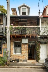 a brick house with a white door and a balcony at Redfern Terrace House l 2 Bedrooms & Loft in Sydney