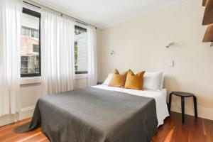 a bedroom with a bed and two windows at Redfern Terrace House l 2 Bedrooms & Loft in Sydney