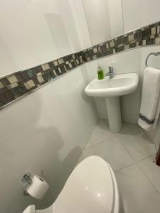 La salle de bains blanche est pourvue de toilettes et d'un lavabo. dans l'établissement HABITACION CON BAÑO COMPARTIDO, à Guayaquil