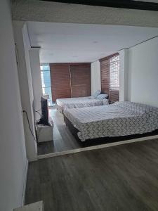 1 dormitorio con 2 camas y TV. en casa en el norte de la ciudad, a 5 minutos del portal norte en Bogotá