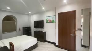 a bedroom with a bed and a television and a door at Rubie Hotel in Ho Chi Minh City