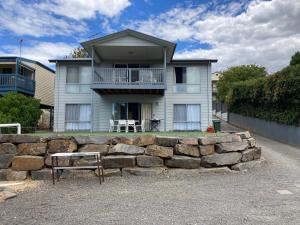 a house with a stone wall in front of it at Bay views on Laurie in Encounter Bay