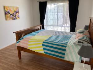 a bedroom with a bed with a colorful comforter and a window at Bay views on Laurie in Encounter Bay