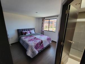 um quarto com uma cama e uma grande janela em Departamento Duplex con Terraza em Cuenca