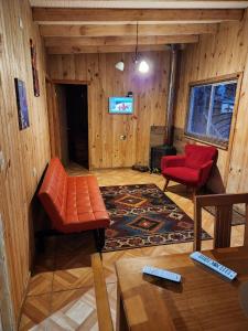 ein Wohnzimmer mit einem Sofa und einem roten Stuhl in der Unterkunft Cabaña 2 Entre Copihues in Osorno
