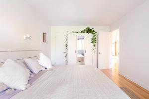 Habitación blanca con cama grande con almohadas en Bright Riverfront 3-Bedroom Condo, en Montreal