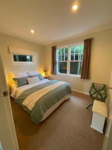 a bedroom with a large bed and two windows at Refined, Retro & Relaxing in Paraparaumu