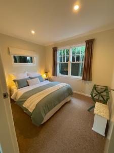 - une chambre avec un grand lit et 2 fenêtres dans l'établissement Refined, Retro & Relaxing, à Paraparaumu