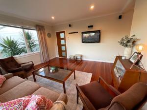 - un salon avec un canapé et une table dans l'établissement Refined, Retro & Relaxing, à Paraparaumu