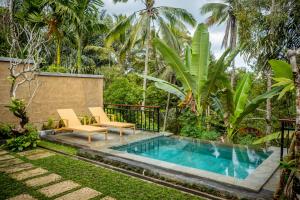 einen Pool in einem Garten mit 2 Stühlen und einem Tisch in der Unterkunft Toya Sutra Villa in Tampaksiring