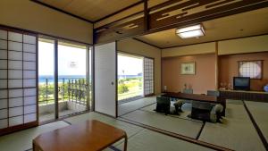 uma sala de estar com uma mesa e vista para o oceano em Hotel Nishinagato Resort em Takibe
