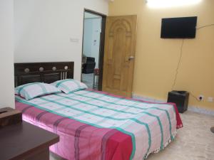 a bedroom with a bed and a television and a door at Golpata Bed & Breakfast in Dhaka