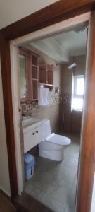 a bathroom with a white toilet and a sink at Raniban Suites - Studio Apartment in Kathmandu