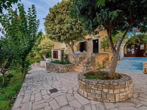 a stone walkway with a tree in front of a house at Group Accomodation, Heliopetra Studios And Houses in Douliana