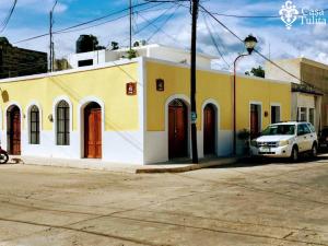 a yellow and white building with a car parked in front at Casa Tulita Valladolid in Valladolid