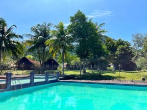 una piscina di fronte a un resort con palme di ALUN ALUN ISLAND RESORT a Kampong Atap Zing