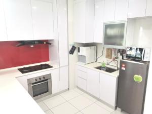 uma cozinha com armários brancos e um frigorífico de aço inoxidável em SkyView em Johor Bahru