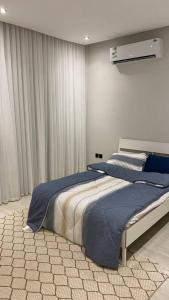 a bedroom with a large bed with blue sheets at Luxury Apartment in Riyadh