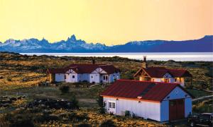 a group of houses in a field with mountains in the background at Estancia La Estela in Lago Viedma