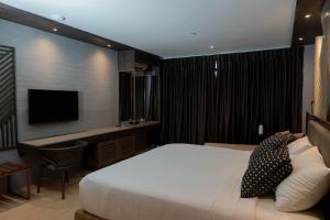 a hotel room with a bed and a television at Adelina Hotel and Suites in Mati