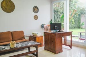 uma sala de estar com um sofá e uma secretária em Villa Prambanan Jogja with Private Swimming Pool by Simply Homy em Sleman