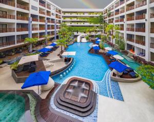 an overhead view of a resort pool with blue umbrellas at Deevana Plaza Phuket - SHA Extra Plus in Patong Beach