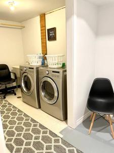 a laundry room with two washing machines and a chair at Furnished Townhouse w parking by Hospital & University! in Thunder Bay