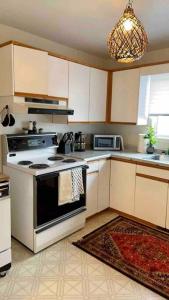 a kitchen with a stove and a microwave at Furnished Townhouse w parking by Hospital & University! in Thunder Bay