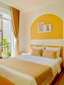 a bedroom with a large bed with a yellow wall at Letters Bà Triệu in Liên Trì (3)