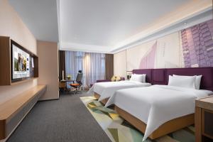 a hotel room with two beds and a tv at Hampton by Hilton Nanning Jiangnan in Nanning