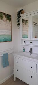 Baño blanco con lavabo y espejo en Conch Club Cottage, en Head of Bay