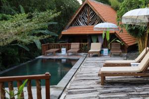 a resort with a pool with chairs and an umbrella at Ubuntu Bali Eco Yoga Retreat - CANGGU in Canggu
