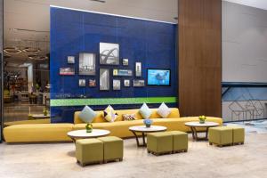 a yellow couch in a lobby with tables and chairs at Hampton by Hilton Nanning Jiangnan in Nanning