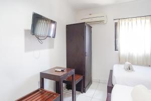 a room with a bed and a tv and a table at Gana Inn Legian in Legian