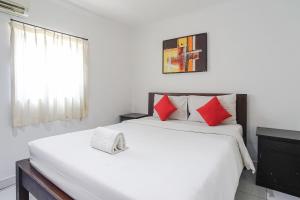 a bedroom with a large white bed with red pillows at Gana Inn Legian in Legian