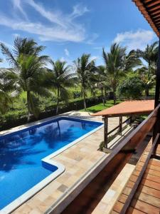 een zwembad naast een resort met palmbomen bij Casa do paiva in Cabo de Santo Agostinho