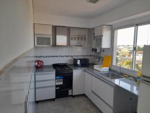 LanúsにあるDepartamento Nuevo y comodo con parkingのキッチン(白いキャビネット、コンロ付)