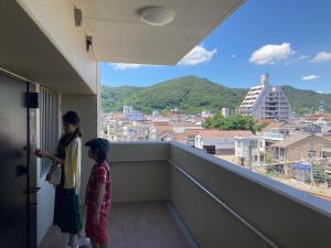 zwei Kinder stehen auf einem Balkon mit Stadtblick in der Unterkunft 笠岡　潮待ちHOTEL 