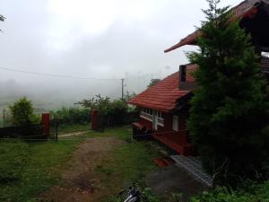 a red house with a tree in front of it at Chilly Coorg in Virajpet