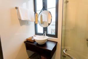 uma casa de banho com um lavatório, um espelho e um chuveiro em Life Boutique Hotel em Hue